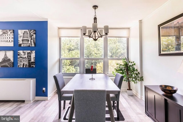 dining room with a notable chandelier, ornamental molding, and light hardwood / wood-style flooring