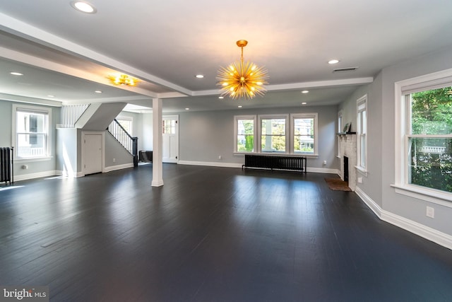 unfurnished living room featuring a notable chandelier, dark hardwood / wood-style floors, and radiator