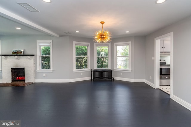 unfurnished living room featuring dark wood-type flooring, beamed ceiling, a notable chandelier, a fireplace, and radiator heating unit