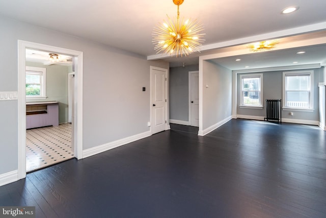 unfurnished living room featuring a chandelier, dark hardwood / wood-style flooring, and a healthy amount of sunlight