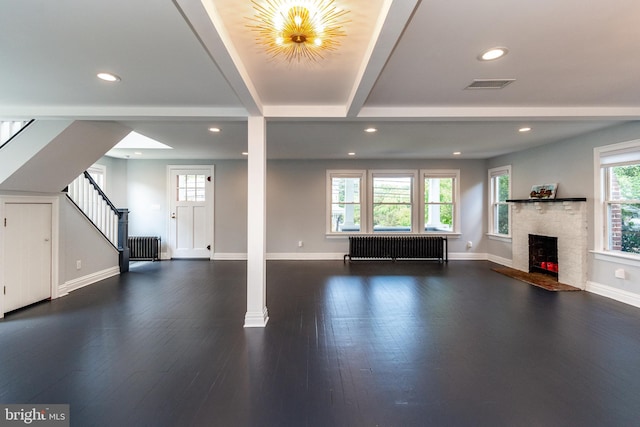 unfurnished living room featuring beam ceiling, radiator heating unit, and dark wood-type flooring