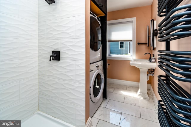 washroom with stacked washer / drying machine and sink