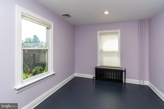 empty room featuring dark hardwood / wood-style flooring and radiator heating unit