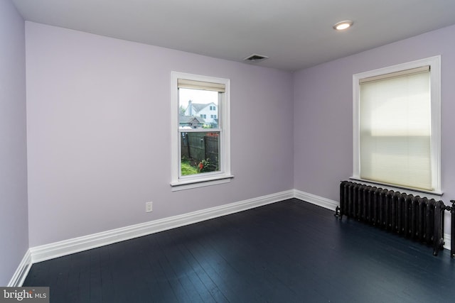 empty room featuring dark hardwood / wood-style flooring and radiator