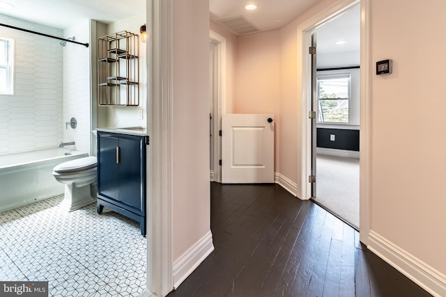 full bathroom with hardwood / wood-style floors, tiled shower / bath combo, toilet, and vanity