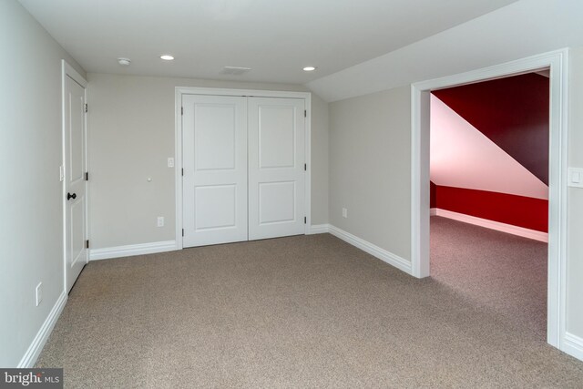 unfurnished bedroom with carpet, vaulted ceiling, and a closet