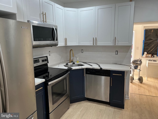 kitchen featuring appliances with stainless steel finishes, tasteful backsplash, light stone counters, sink, and white cabinetry