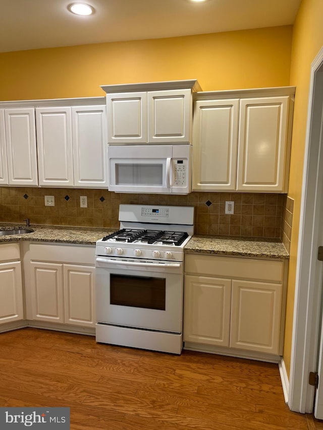 kitchen featuring light stone counters, backsplash, white appliances, white cabinets, and light wood-type flooring