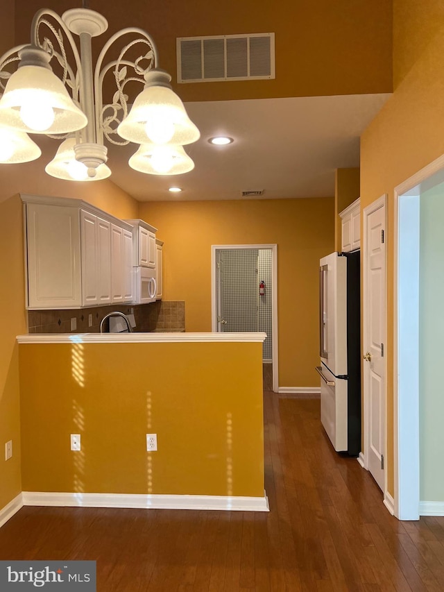 kitchen with hanging light fixtures, high end refrigerator, dark hardwood / wood-style flooring, kitchen peninsula, and white cabinets