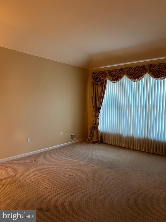 carpeted empty room featuring lofted ceiling