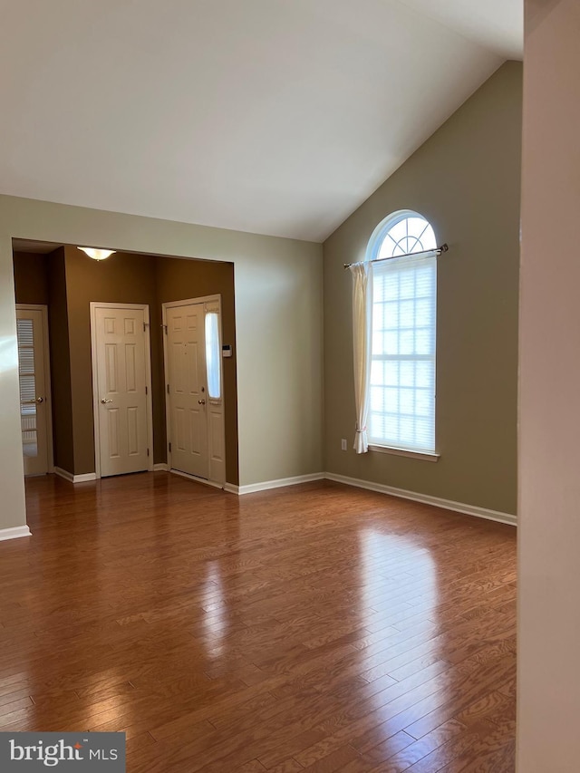 spare room featuring dark hardwood / wood-style floors and lofted ceiling