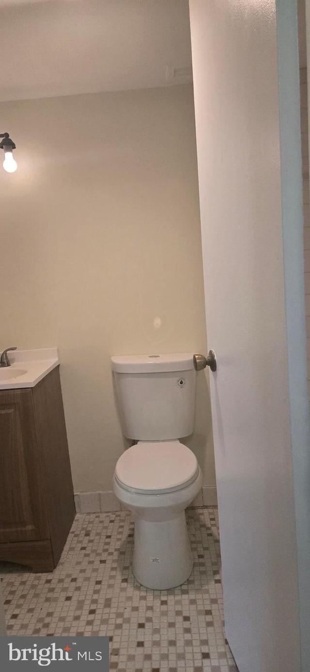 bathroom with toilet, vanity, and tile patterned floors