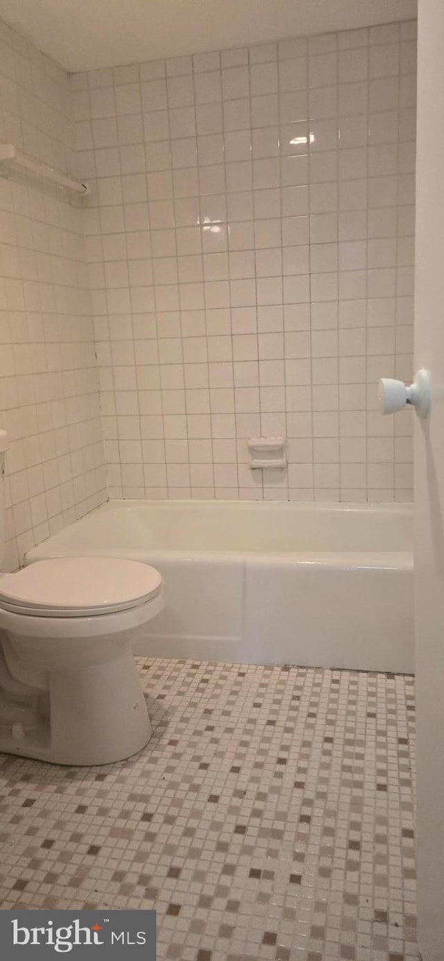 bathroom with toilet, tiled shower / bath, and tile patterned flooring