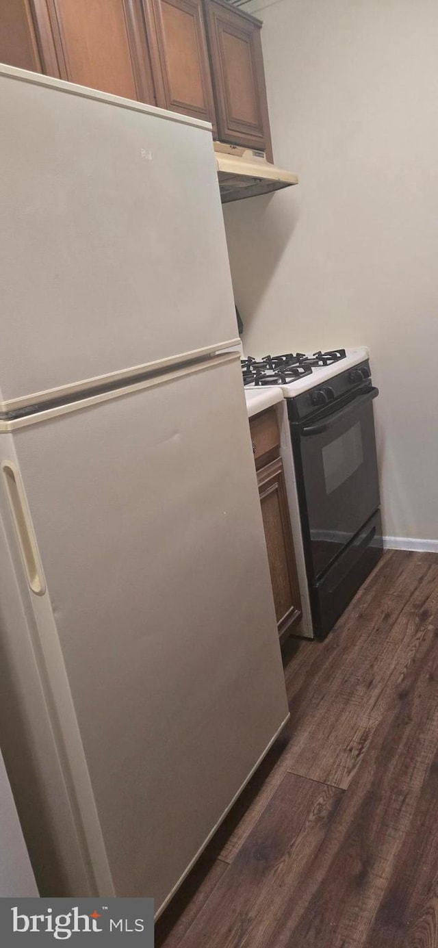 kitchen with gas range oven, refrigerator, and dark hardwood / wood-style floors