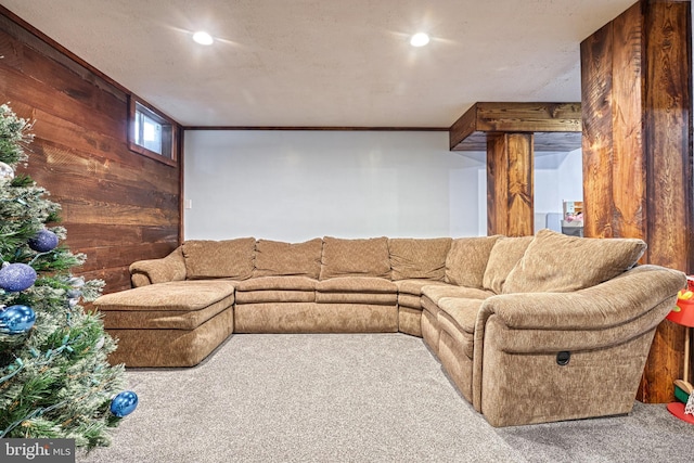 carpeted living room featuring wood walls and ornamental molding