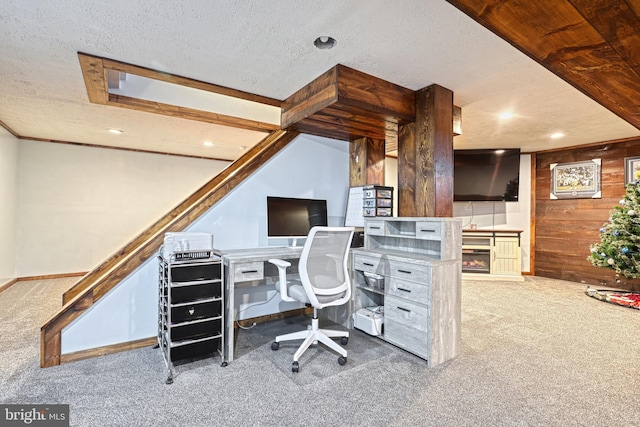 carpeted home office featuring a fireplace, a textured ceiling, and wooden walls