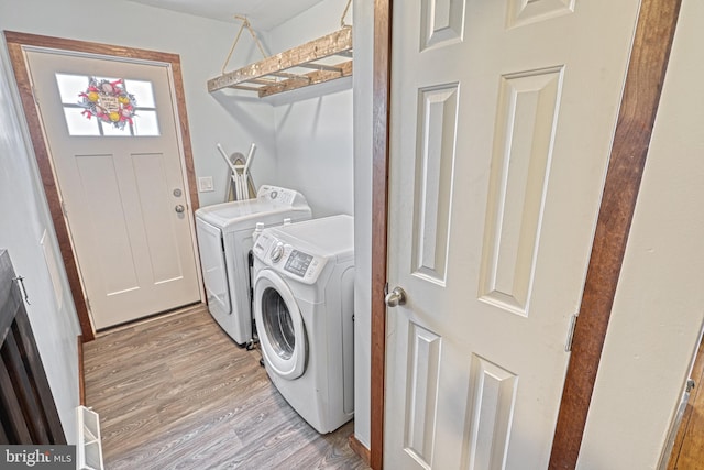 clothes washing area with washing machine and dryer and light hardwood / wood-style flooring