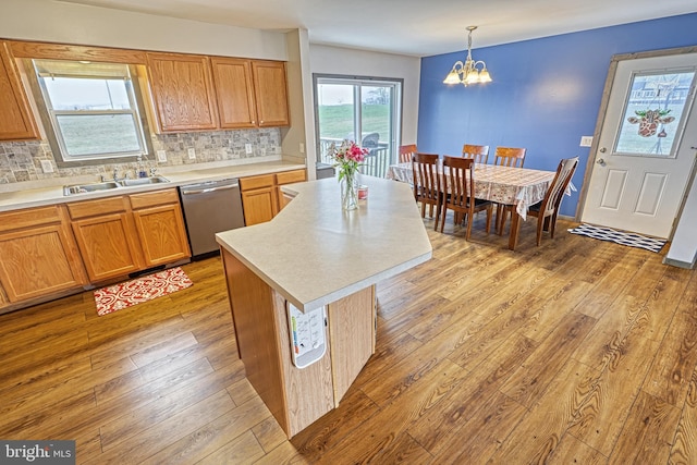 kitchen with stainless steel dishwasher, sink, a notable chandelier, a center island, and hanging light fixtures