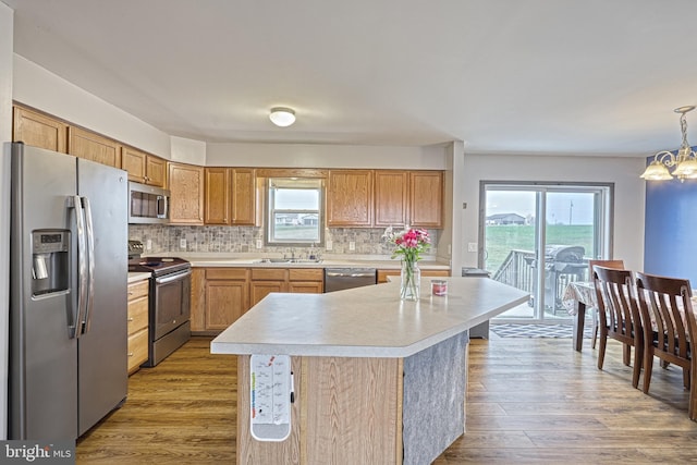 kitchen featuring a center island, tasteful backsplash, a chandelier, pendant lighting, and appliances with stainless steel finishes