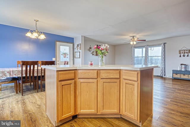 kitchen with ceiling fan with notable chandelier, light hardwood / wood-style flooring, a kitchen island, and decorative light fixtures