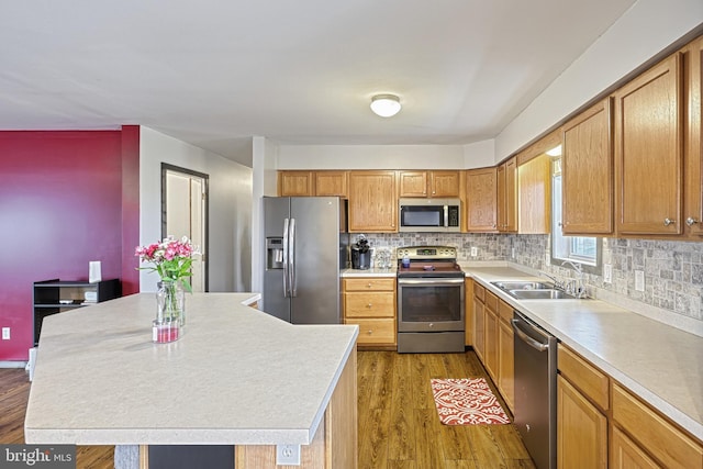 kitchen with light wood-type flooring, backsplash, stainless steel appliances, sink, and a kitchen island