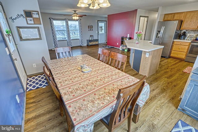 dining room featuring ceiling fan with notable chandelier and dark hardwood / wood-style floors