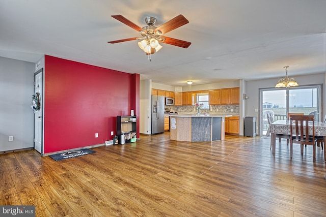 kitchen featuring a center island, wood-type flooring, stainless steel appliances, and hanging light fixtures