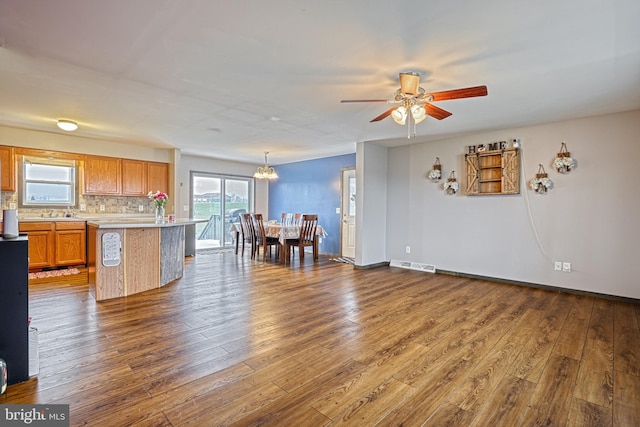 kitchen featuring a center island, hanging light fixtures, tasteful backsplash, dark hardwood / wood-style floors, and ceiling fan with notable chandelier