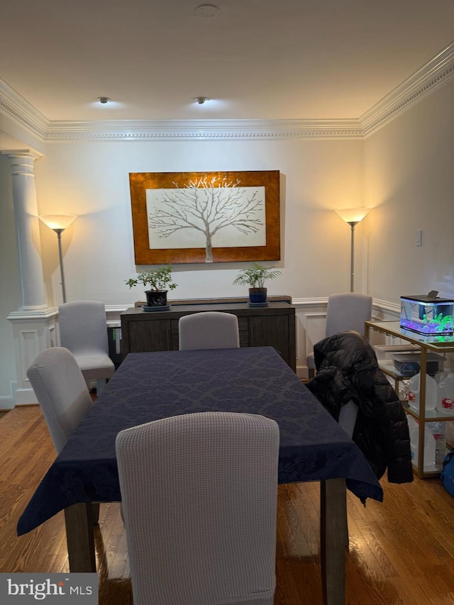 dining room featuring hardwood / wood-style floors, ornamental molding, and ornate columns