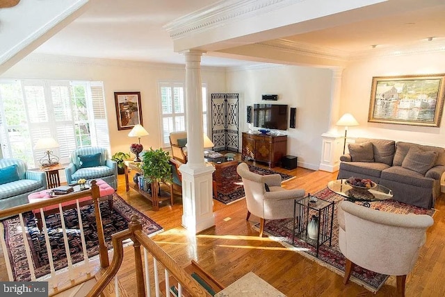 living room featuring hardwood / wood-style flooring, crown molding, and ornate columns