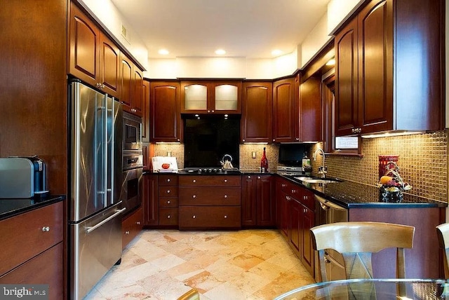 kitchen featuring sink, backsplash, dark stone counters, and appliances with stainless steel finishes