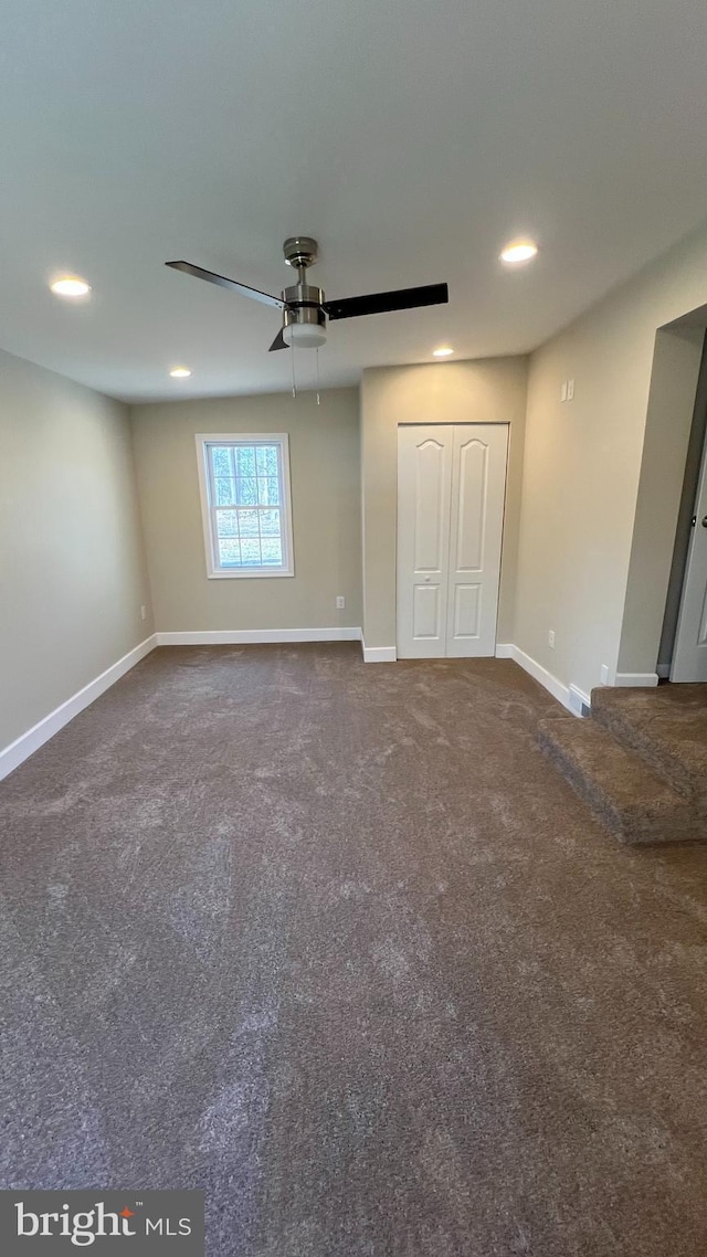 unfurnished bedroom featuring dark colored carpet, a closet, baseboards, and recessed lighting