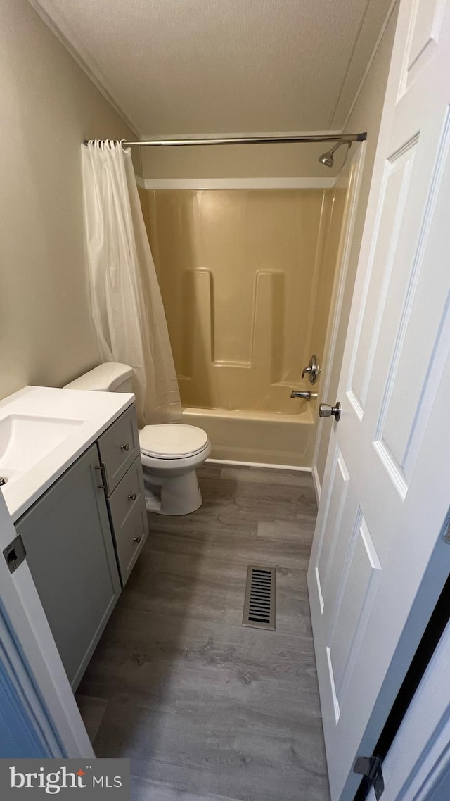 full bathroom featuring visible vents, toilet, wood finished floors, shower / bath combo with shower curtain, and vanity