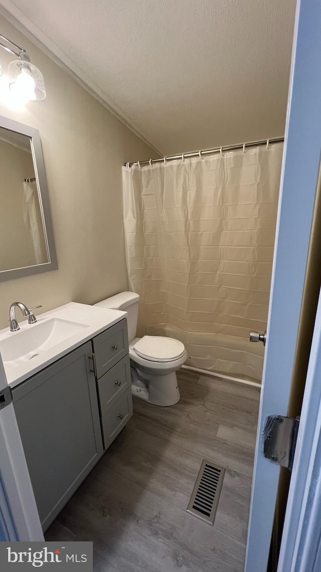 bathroom featuring toilet, visible vents, wood finished floors, and vanity