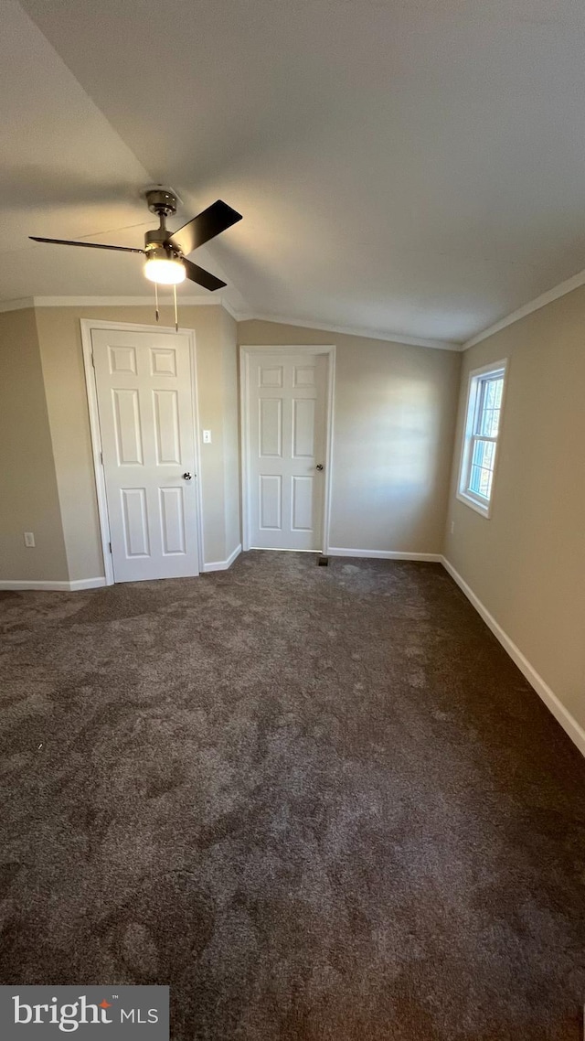 unfurnished bedroom with ornamental molding, dark carpet, baseboards, and a ceiling fan