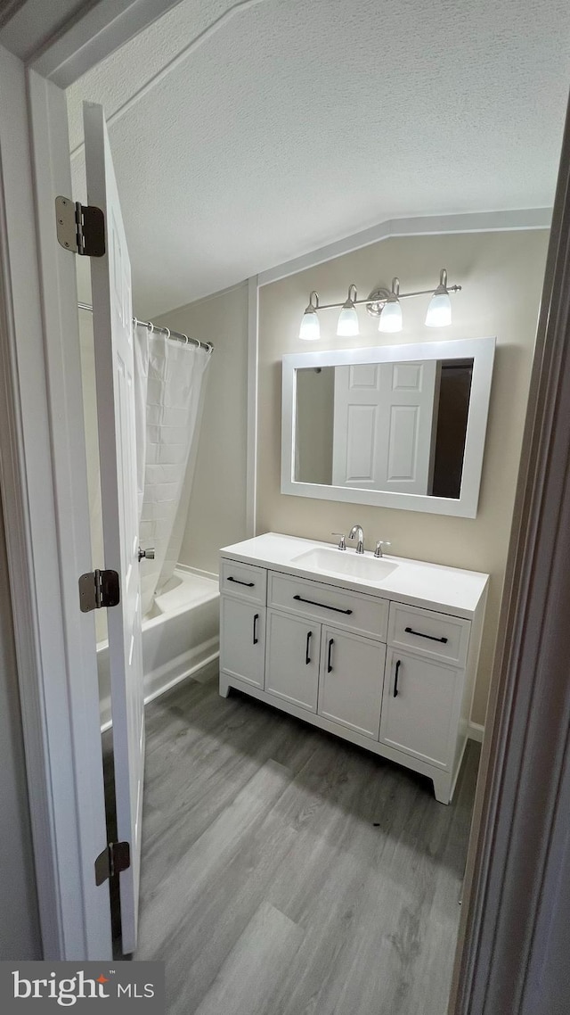 bathroom featuring a textured ceiling, shower / tub combo, wood finished floors, and vanity