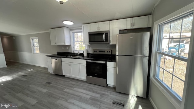 kitchen with dark countertops, white cabinetry, appliances with stainless steel finishes, and a sink