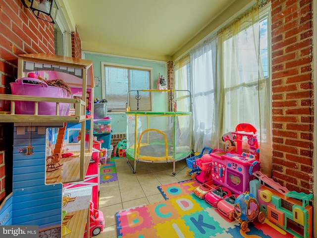 rec room with tile patterned floors and brick wall