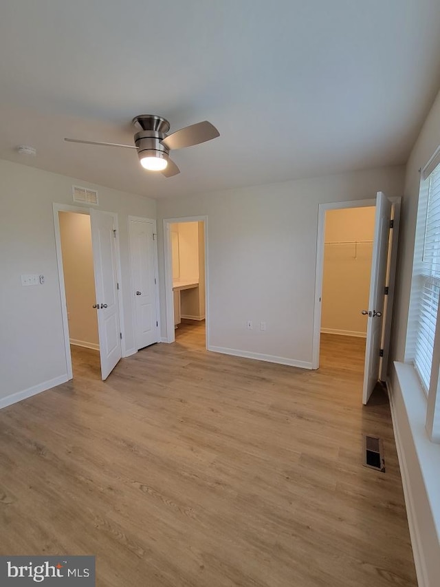 unfurnished bedroom featuring ceiling fan, a spacious closet, and light hardwood / wood-style flooring