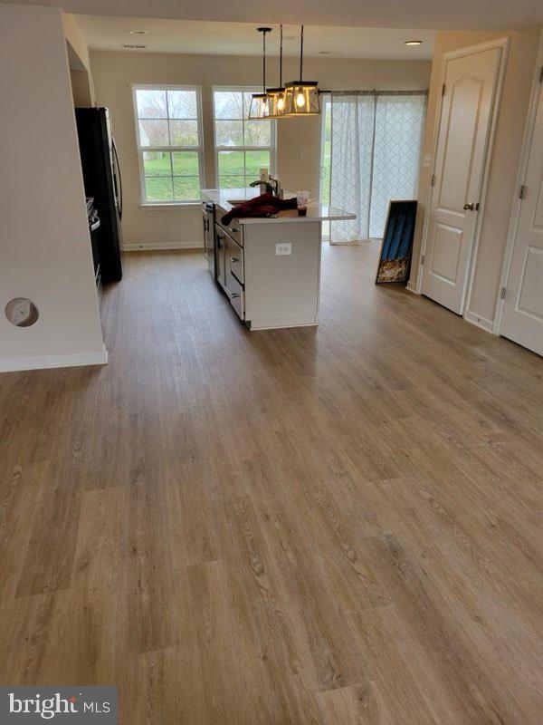 kitchen with pendant lighting, black fridge, and light wood-type flooring