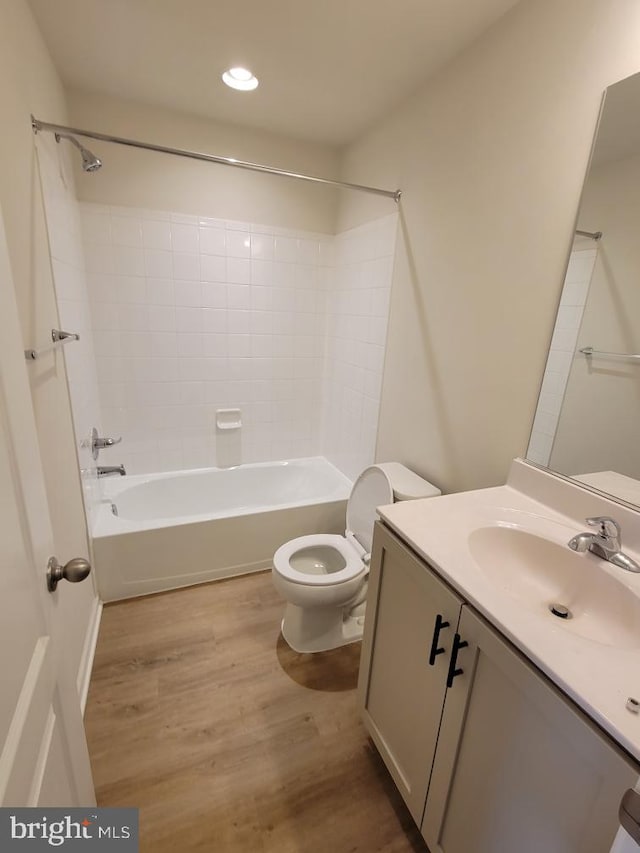 full bathroom with hardwood / wood-style flooring, vanity, toilet, and washtub / shower combination