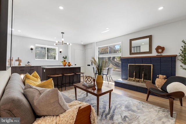 living room with light wood-type flooring, a tile fireplace, and a chandelier