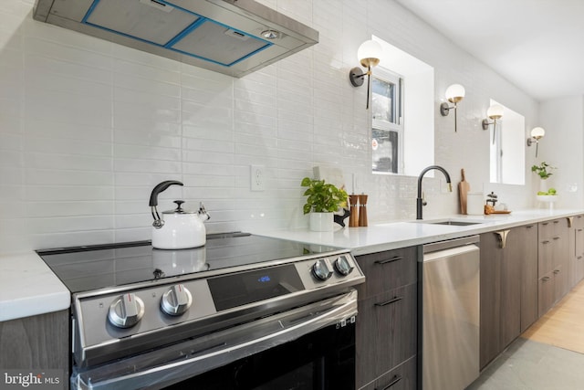 kitchen with sink, backsplash, decorative light fixtures, dark brown cabinets, and appliances with stainless steel finishes