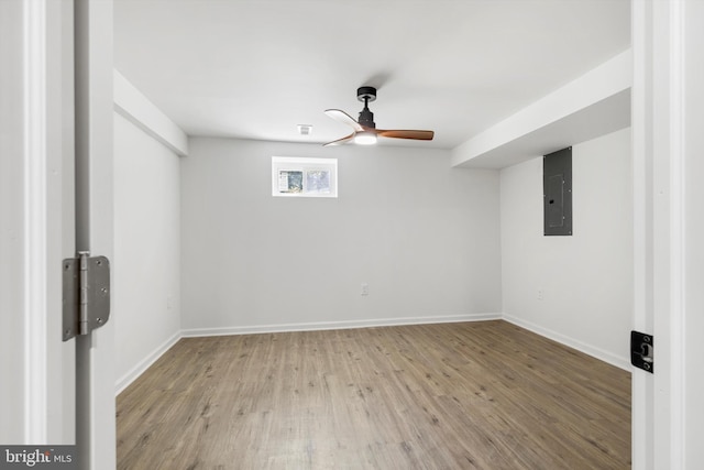 basement featuring ceiling fan, light wood-type flooring, and electric panel