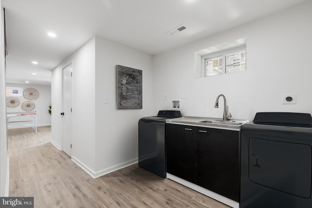 laundry area featuring washer and clothes dryer, sink, and light wood-type flooring