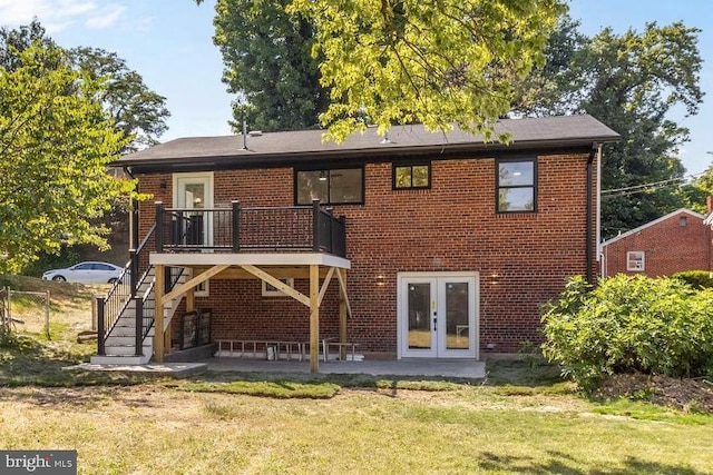 rear view of property with a yard, a wooden deck, french doors, and a patio