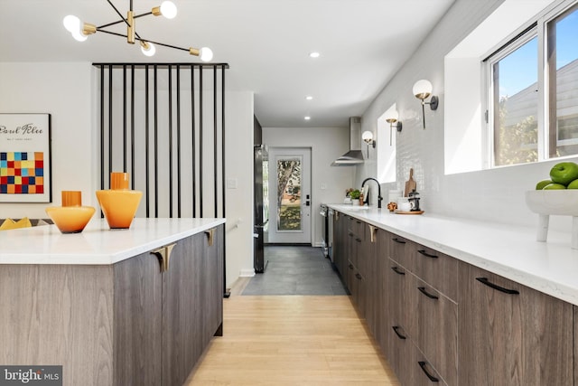 kitchen featuring a notable chandelier, plenty of natural light, wall chimney exhaust hood, and a breakfast bar area