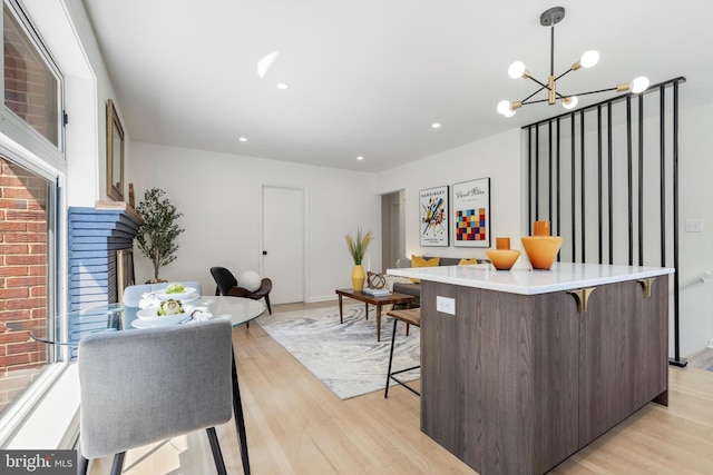 kitchen with a breakfast bar, dark brown cabinetry, a notable chandelier, light hardwood / wood-style floors, and hanging light fixtures