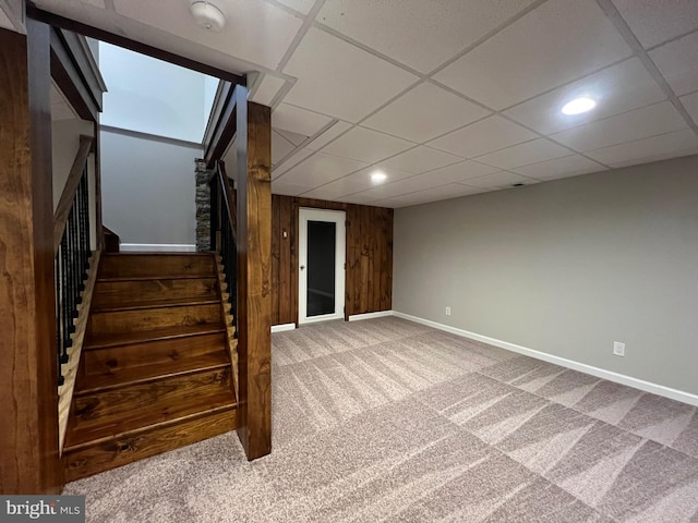 interior space featuring carpet floors, a paneled ceiling, and wood walls