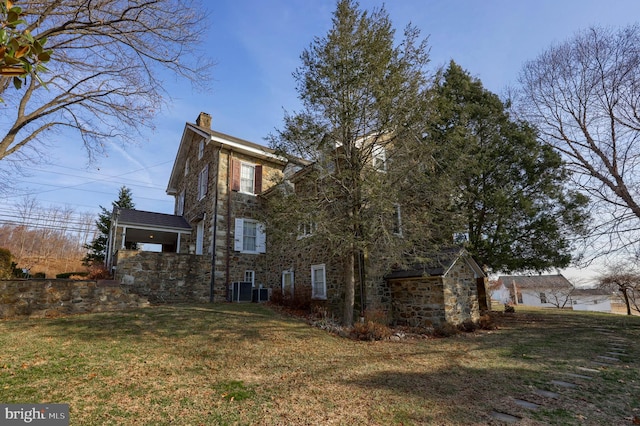 view of side of home with a lawn and cooling unit